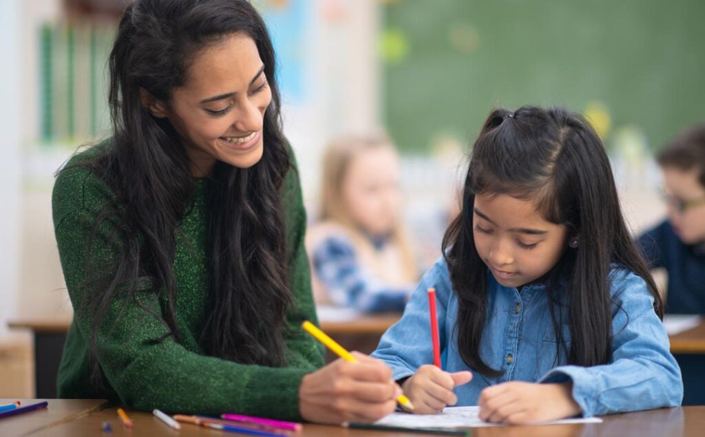 A teacher doing a personalized English lessons helps her student understand the words in a story book.